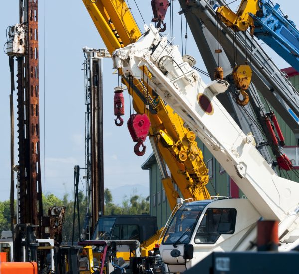 A group of mobile cranes with hooks and pulleys, dockyard lifting equipment.