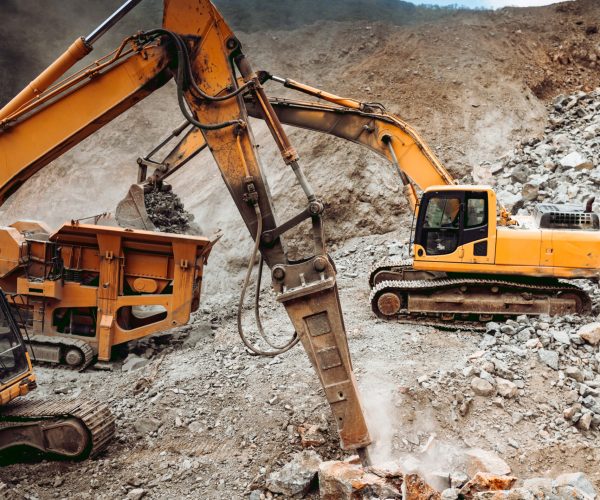 Hydraulic crusher and track type excavator backhoe machinery working. Industrial machineries working on open pit mine, ore quarry